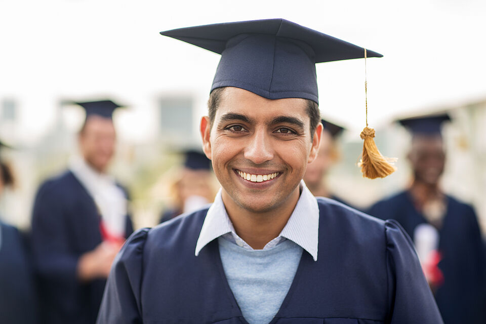 lächelnder Studierender mit Absolventenhut